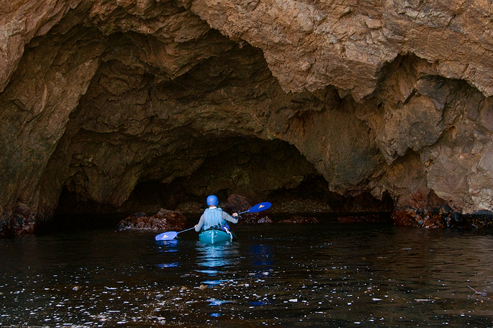 kayaker paddling into sea cave